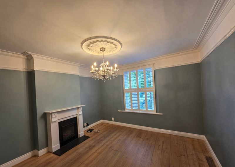 Finished lounge with green walls, white ceiling and fireplace